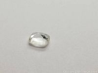 Front angle view of white sapphire cushion cut gemstone on a plain background.