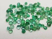 Overhead view of scattered loose green emeralds on white background