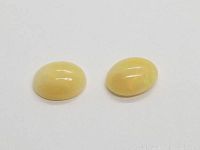 Two oval cabochon yellow Ethiopian opals side by side on white background showing smooth domed shape and yellow color.