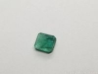 Clear image of the cushion cut green Colombian emerald on a white background showing the cut and color.