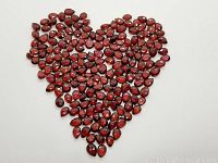 Lot of pear-shaped, checkerboard cut red garnets arranged in heart shape on white background.