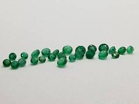 Front angle view showing mixed sized oval and round emeralds with good green color and natural inclusions.