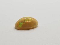 Side view of the oval light chocolate opal cabochon showing curved surface and vibrant internal colors.