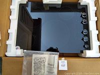 Cooktop in original packaging with protective foam and instruction manual visible