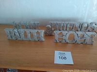 Decorative wall hangings spelling Faith, Hope, Love, Friends, and ampersand symbol on wood surface.