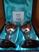 Two Wm. Rogers silverplate goblets resting inside a satin-lined blue case with branding on lid interior.