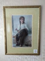 Full view of framed art print showing young girl sewing, with gold frame and green matting