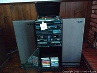 Photo of Yorx Newave combination stereo system with two speakers and 16 cassette tapes in storage below.