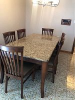 Six matching wooden chairs arranged around a granite-top table, showing overall appearance and finish of frames and seats.