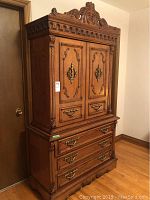 Front view of two-piece wooden dresser showing ornate carved details and hardware.
