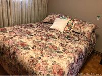 Full view of orthopaedic bed covered in floral bedding with pillows.