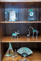 Shelf with brass candle holder, squirrel figurine, clock, and other brass animal figurines including giraffes and elephant.