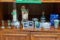 Wide shot showing collection of pewter frames, candle holders, crystal vase, and decorative items on wooden cabinet