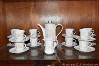 Full display of the tea set arranged on a wooden shelf showing teapot, creamer, 12 cups and 12 saucers