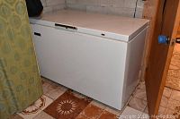 Full view of the white Viking chest freezer with front lid and handle, situated on tiled floor, showing size and condition.