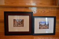 Two framed Roma prints side-by-side on wooden surface, showing Piazza Navona and Spanish Steps scenes.