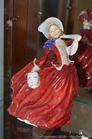 Full front view of Royal Doulton Autumn Breezes figurine showing red dress, bonnet, and muff.