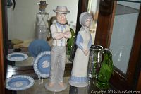Photo showing two ceramic figurines (man and woman), two Wedgwood Jasperware plates reflected in mirror and pewter mug
