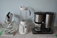 Full lot showing Sunbeam Mixmaster mixer with glass bowls on left, white Problend blender in center, and stainless steel PC coffeemaker on right.