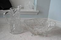 Photo showing cut crystal pitcher and etched leaded glass bowl on carpet near window, overall view of set.