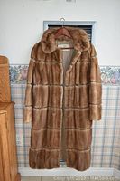 Front view of the light brown full-length fur coat with horizontal stitching and wide collar.