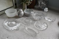 View of all ten glass and ceramic serving pieces arranged on floor showing variety including bowls, jars, dishes and casseroles.