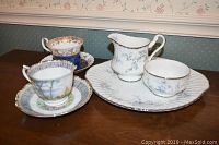 Photo of two Royal Albert teacups with matching saucers and Paragon creamer and sugar bowl on the Paragon serving plate.