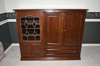 Front view of wooden entertainment unit showing beveled glass door, two wooden doors, and drawer below