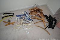 Overview of all various hangers laid out on floor including wooden, plastic, pant, and suit hangers