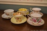 Five teacup and saucer sets displayed together showing different designs and brands.