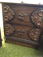 Two dark wood tone night stands with ornate carved wooden corner designs and metal drawer handles, showing front view, each with two drawers.