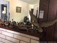 Full view of all brass items lined up on a shelf, showing the eagle, various birds, and animals