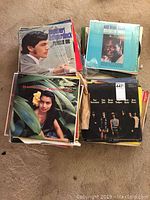 Four stacks of vintage vinyl record albums on the floor, showing multiple album covers in varying condition.