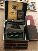 Typewriter in open case with accessories and books around