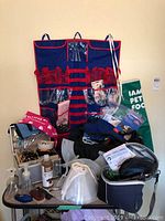 Photo showing folding table topped with grooming supplies including nail groomers, apron, organizer, grooming products, and various pet care items