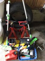 Overview photo showing tire jacks, gas can, tire, cleaning brushes and assorted cleaning supplies in basket