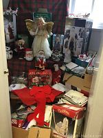 Full lot view showing assorted Christmas decorations, including angel figure, Santa dolls, snowman figurines, and boxes of holiday decor items.