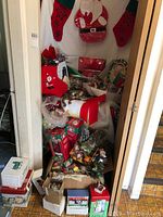 Full box filled with various Christmas decorations including stockings, ornaments in boxes, and bags of decor