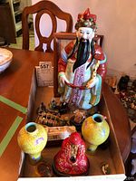 Boxed arrangement showing large porcelain deity figurine, vases, red Buddha incense holder, and smaller figurine