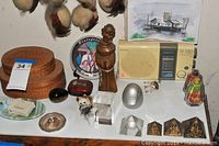 Various items including vintage Sony radio, clothes brush, wooden figurine, pyramid crystals, and small collectibles arranged on a white surface.