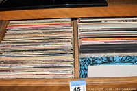 Drawer containing approximately 200 33 RPM vinyl records stored vertically with various album covers visible.