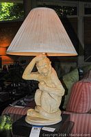 Full lamp showing monkey sculpture and pleated lampshade on base.