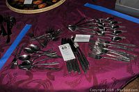 Overview of all flatware pieces laid out on a purple tablecloth to show quantity and style.