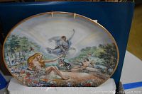 Front view of a decorative plate showing artwork of 'The Creation' with natural scene and characters
