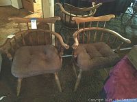 Two matching wooden armchairs side by side, showing shape, cushions, and wood finish.