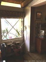 Full view of the lamp positioned next to a window and potted plant, showing entire height and placement.