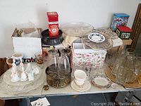 Wide view of lot showing various glass platters, tins, ceramic decor, and tea sets