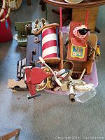 Overall collection of vintage toys on carpet, showing tricycle, barber pole, Mickey Mouse pop-up box, wooden shoes, musical instruments, and various wooden toys