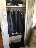 Closet view showing several men's suit jackets, wool coat, shirts, and sweatpants hanging neatly, some with original price tags.