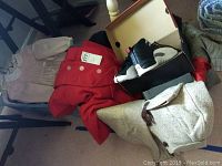 Youth size 4.5 Air Jordan XII shoes with black, white, and red detailing, next to assorted youth coats and clothing including a red coat and pink dress.